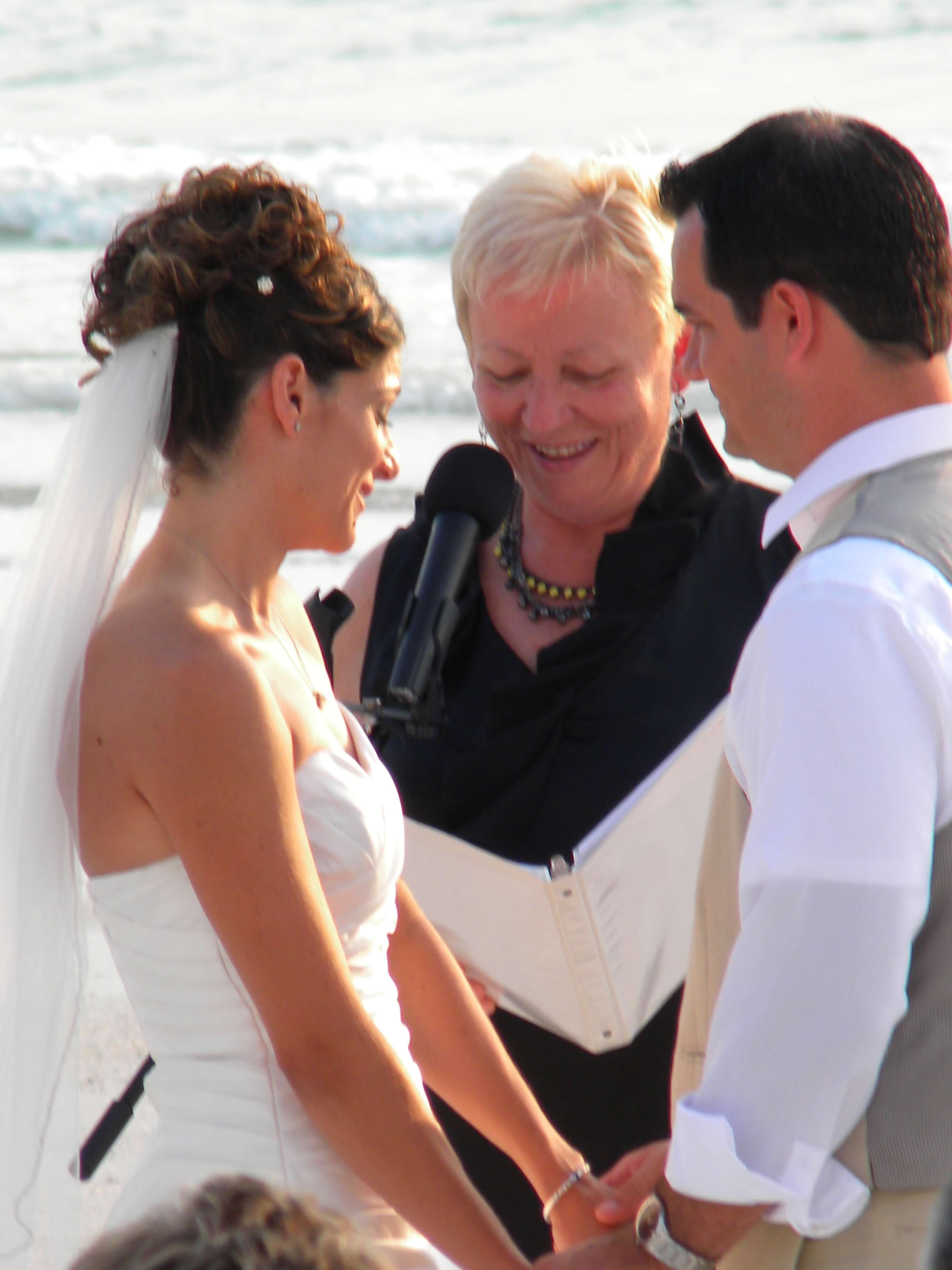 Eileen (wedding officiant) wearing black officiating a beach wedding